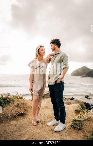 Stylish couple standing on a cliff over the ocean Stock Photo