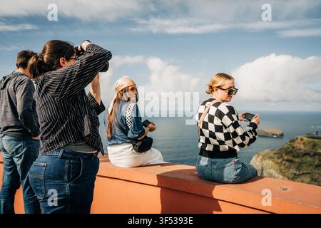 Friends take photos at scenic ocean viewpoint Stock Photo