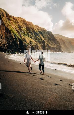 Young couple holding hands running on a remote beach Stock Photo