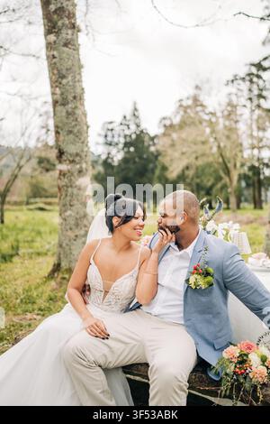 Bride affectionately touches groom's face outside Stock Photo