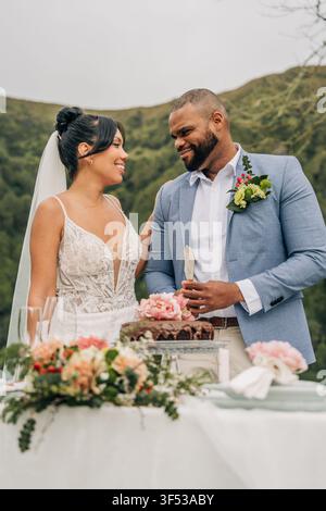 Happy newlywed couple smiling before cutting wedding cake Stock Photo