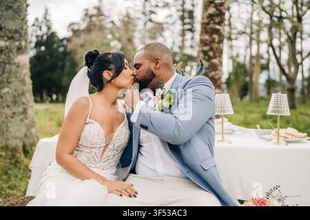 Newlywed couple share a romantic kiss outdoors Stock Photo