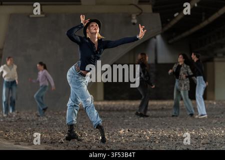 Expressive female dancer striking a pose under a bridge Stock Photo