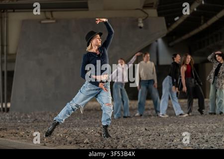 Female street dancer leads crew in urban underpass Stock Photo