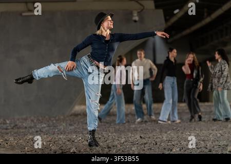 Stylish woman performing dance move in urban setting Stock Photo