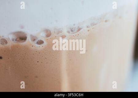 Macro shot highlighting the rich texture of creamy coffee foam and delicate bubbles forming on the surface of a freshly brewed hot beverage in a mug. Stock Photo