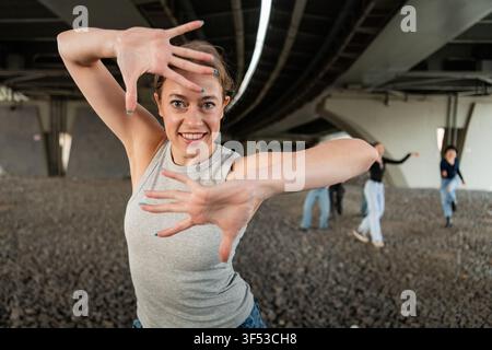 Woman smiles framing face with hands while dancing Stock Photo