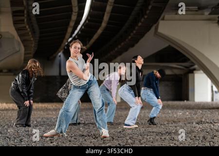 Young women practicing a street dance routine under a bridge Stock Photo