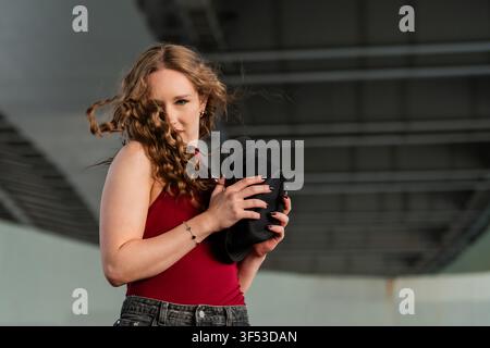 Young woman with windblown hair holding a black hat Stock Photo