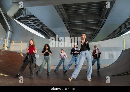 Young dance crew practicing routine under a bridge Stock Photo
