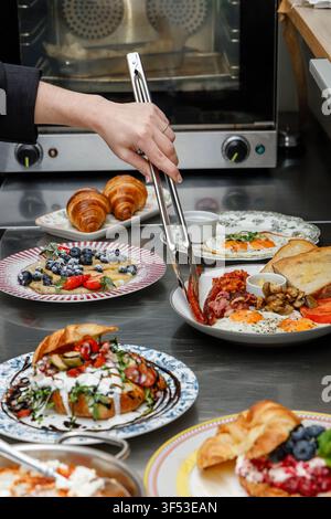 A female chef is preparing breakfasts in a restaurant. Stock Photo