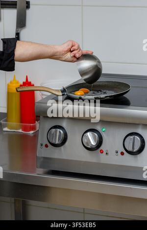 A female chef is preparing breakfasts in a restaurant. Stock Photo