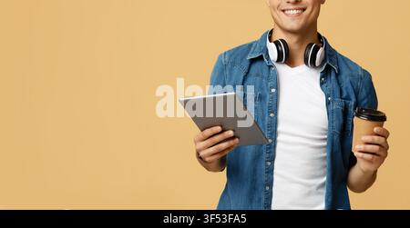 Work and play with online gadget. Positive friendly young student with headphones hold digital tablet Stock Photo