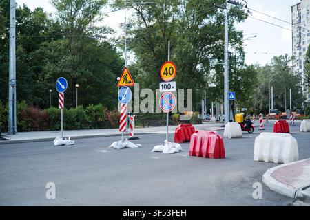 Road repair signs and plastic barriers blocking city street work zone Stock Photo