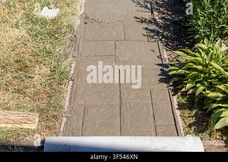 Freshly Stamped Concrete Surface with Decorative Stone Pattern During Garden Path Construction Stock Photo