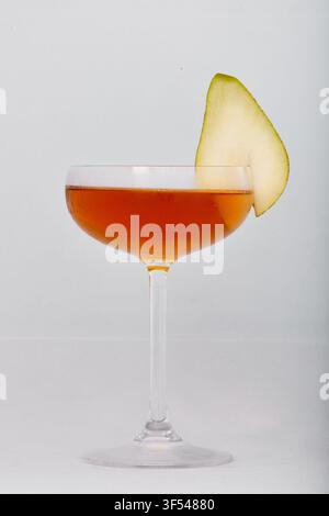 An amber stemmed cocktail with a pear garnish is photographed against a white background in London, England, United Kingdom, on 16 July 2018. Stock Photo