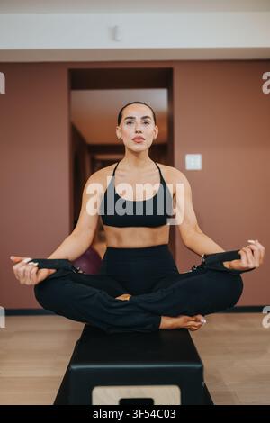 Fit woman practicing seated meditation and yoga during an indoor workout session on a bench Stock Photo