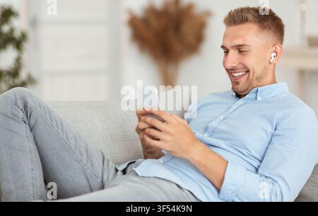 Happy man listening to music sitting on sofa Stock Photo