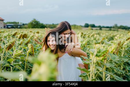 Two beautiful young women having fun in a sunflower Stock Photo