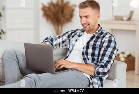Happy freelancer chatting online on laptop at home Stock Photo