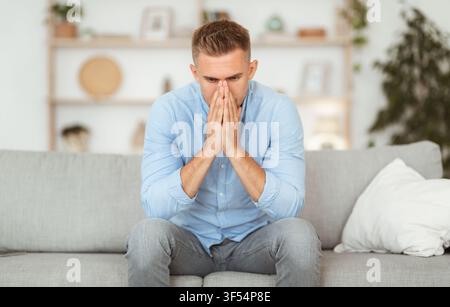 Depressed sad man sitting on couch, thinking about problems Stock Photo
