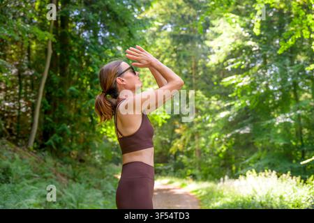 Woman practicing yoga and meditation on a sunny forest trail Stock Photo