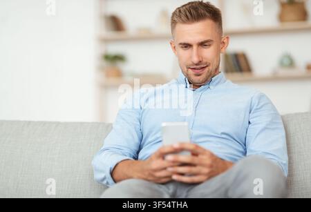 Handsome adult man using smartphone at home Stock Photo