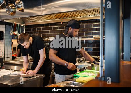 Chefs working in professional restaurant kitchen preparing food Stock Photo