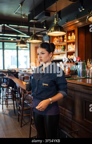 Young adult waitress working in restaurant bar holding tray Stock Photo