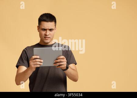 Strange video, shocking information, weird message. Surprised and upset man looks in digital tablet and reads news Stock Photo