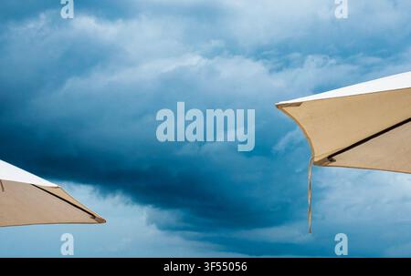 White beach umbrellas set against a dramatic, stormy sky. Stock Photo