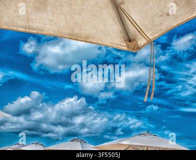 large beach umbrellas against a cloudy blue sky Stock Photo