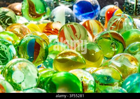Assorted glass marbles reflecting light, showcasing vibrant colors and transparent spheres Stock Photo