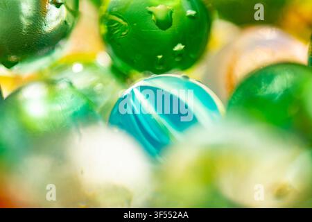 Green and blue glass marbles covered in water with abstract reflections Stock Photo