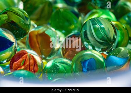 Glass marbles in various colors capturing reflections and light, recalling childhood play Stock Photo
