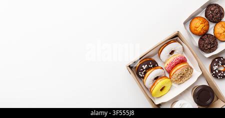 Sweets, unhealthy and fast food. Donuts with different glaze, cupcakes and chocolate muffins in boxes and two coffees in paper cups to go Stock Photo