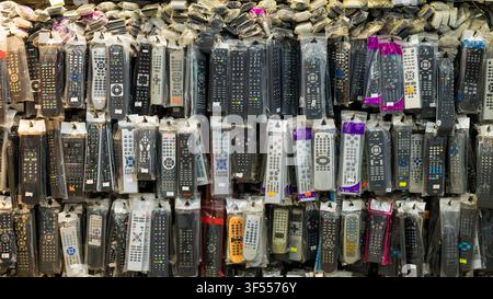 Many different TV remote controls in plastic packaging hanging on a shop display wall Stock Photo
