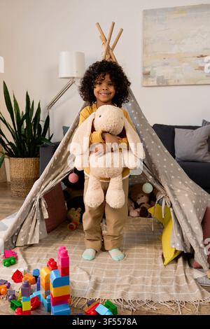 A cheerful african american boy plays indoors with a stuffed animal and colorful blocks Stock Photo