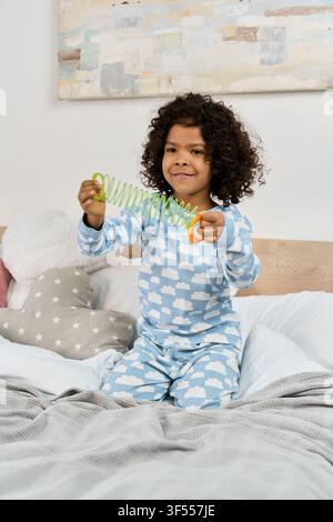 Delighted african american boy enjoys playing with a colorful slinky toy in his cozy bedroom Stock Photo