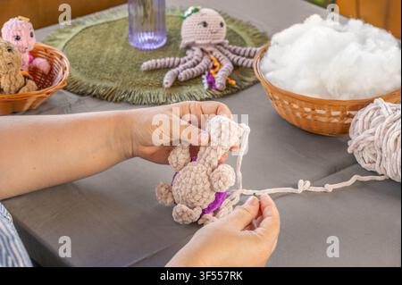Close up of woman hands holding knitted part of plush crochet turtle toy. Creative handmade hobby craft and amigurumi making process Stock Photo