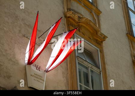 VIENNA, AUSTRIA - JULY 25, 2026: Austrian flags on facade of historic Grosses Michaelerhaus. Stock Photo