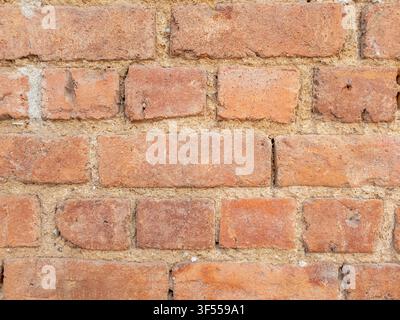 Brick wall features a textured pattern, displaying the individual reddish brown bricks joined by mortar, creating a rustic background Stock Photo