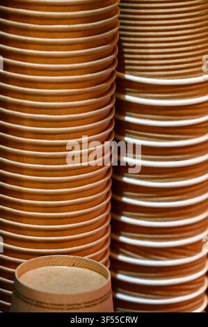 Close-up vertical background view of stacked disposable paper coffee cups in a cafe or restaurant setting. Stock Photo