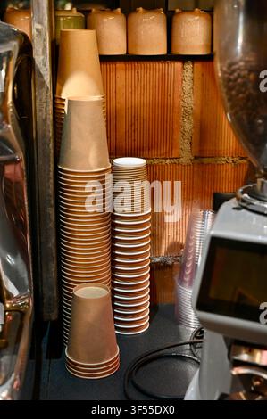 Close-up vertical background view of stacked disposable paper coffee cups in a cafe or restaurant setting. Stock Photo