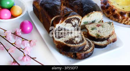 Traditional Romanian Cozonac with walnut, cocoa swirl and turkish delight. Sliced sweet bread with festive colored eggs. Stock Photo