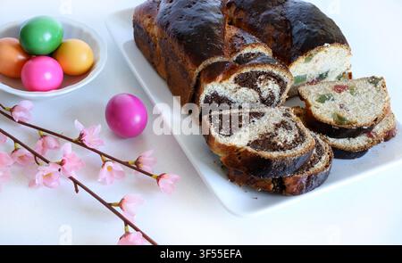 Traditional Romanian Cozonac with walnut, cocoa swirl and turkish delight. Sliced sweet bread with festive colored eggs. Stock Photo