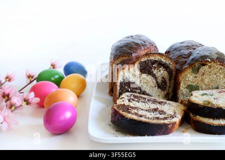 Traditional Romanian Cozonac with walnut, cocoa swirl and turkish delight. Sliced sweet bread with festive colored eggs. Stock Photo