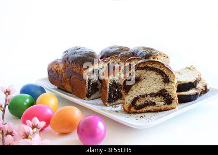 Traditional Romanian Cozonac with walnut, cocoa swirl and turkish delight. Sliced sweet bread with festive colored eggs. Stock Photo