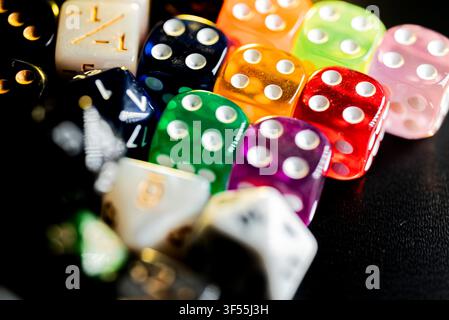 Assortment of multi colored gaming dice resting on a dark surface ready for rolling Stock Photo