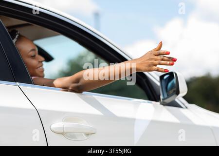 Carefree black woman looking through car window and smiling Stock Photo